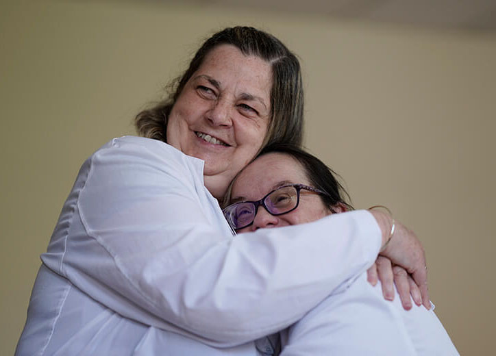 Dos mujeres posan a cámara abrazadas y sonrientes