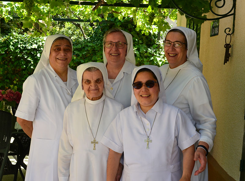 Grupo de cinco monjas vestidas de blanco posan sonrientes a cámara
